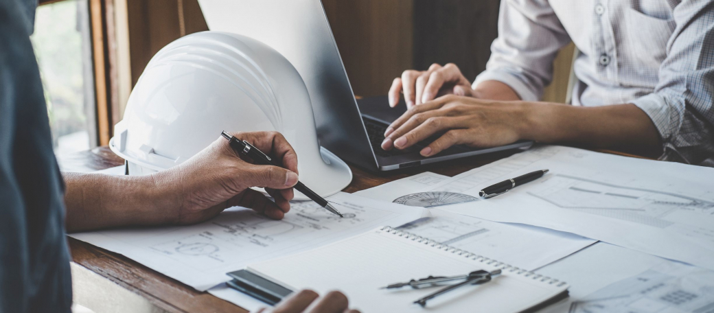 Men by a table with drawings