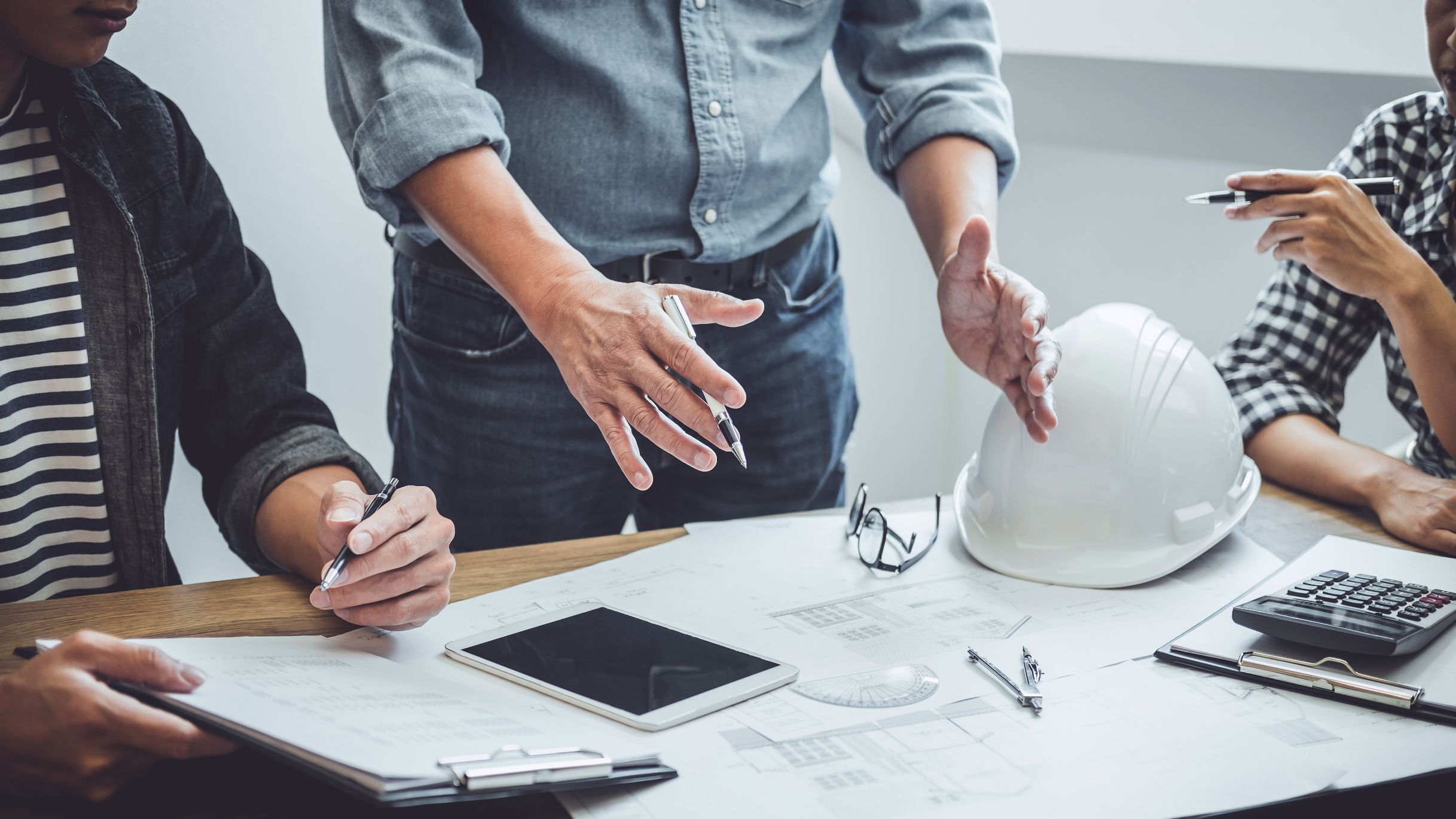 Men planning construction on a table with drawings